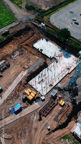 Drone footage showing the beginning stage of construction with excavated ground and completed concrete foundations.