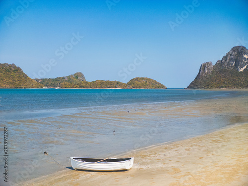 Peaceful boat resting on sandy shores near lush green cliffs