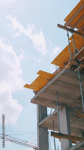 Side view of a residential building under construction with exposed concrete slabs and structural elements.