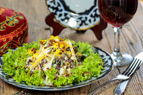 Salad with lettuce, meat, and egg on a decorative plate with wine
