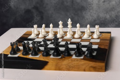 Fotografie Chessboard featuring a complete set of white and black chess pieces arranged and ready for a game