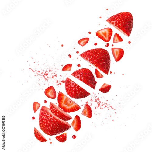 Fresh red strawberries sliced and falling through air with fruit particles