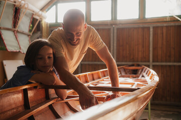 Father and son working together on a wooden boat in a sunny workshop