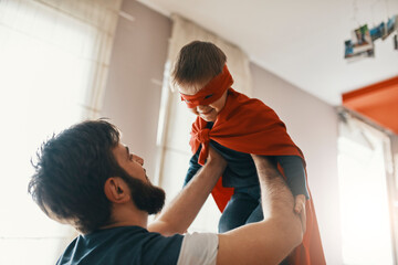 Father playing with his little son dressed up as a superhero