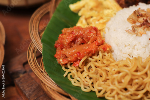 Warm rice, noodles, and spicy sambal served on banana leaf