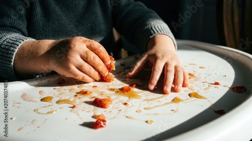 Close-up of a Young Child's Hands Playing with Messy Food on a White High Chair Tray
