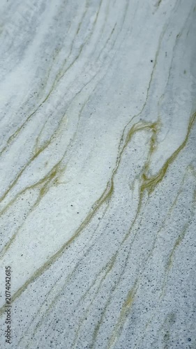 Close-up of naturally formed foam drifting slowly across the water surface, creating unique abstract textures and elegant flowing patterns for creative backgrounds and motion graphics.