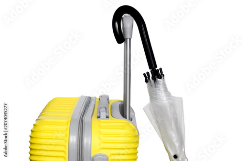 Bright yellow hardshell travel luggage with a folded clear umbrella hooked on the handle