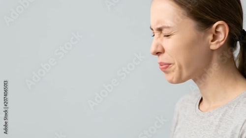Young woman checking her bad breath by blowing air into her hand. Halitosis, oral hygiene, and dental health problem concept.