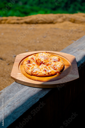 Pizza on a wooden tray, with a beautiful mountain view as a backdrop.
