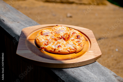 Pizza on a wooden tray, with a beautiful mountain view as a backdrop.
