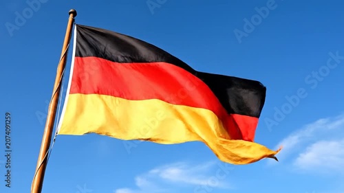 The German national flag waves against a clear blue sky