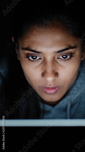 A focused viewer studies a glowing screen under cool blue light