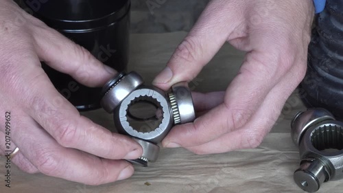Auto mechanic inspects new internal CV joint tripod, Mechanic holds three-way CV joint bearing for replacement