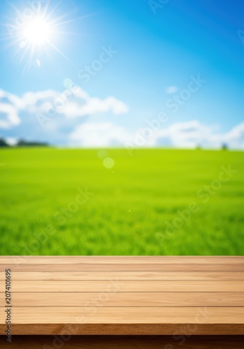 A simple empty wooden table surface stands outdoors in nature, providing copy space overlooking a vibrant green field and bright blue sky, relaxation, sky, copy space