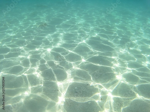 Underwater split view of crystal clear turquoise sea water with sandy bottom