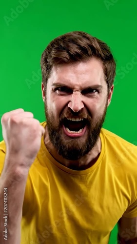 A furious man in a yellow shirt clenches fist in triumph