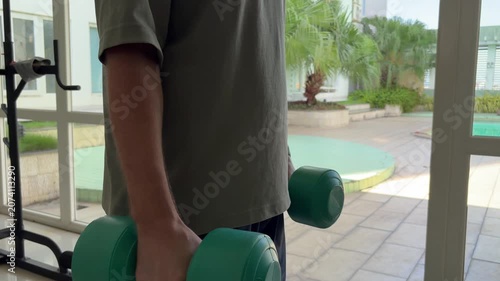 Video of a man performing dumbbell exercises in a modern gym. Fitness and strength training concept representing an active lifestyle, muscle building and personal health.