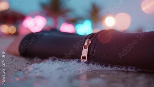 A Close-Up View of a Wet Zippered Wetsuit on the Beach at Dusk with Soft Bokeh Lights in the Background Creating a Dreamy Ambiance of Evening Relaxation