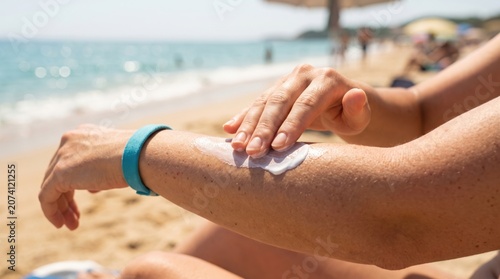 Applying sun protection lotion on skin for UV ray prevention during summer