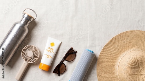 Flat lay of heatwave essentials including sunscreen, water bottle, and cooling accessories