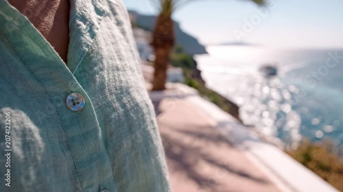 A Close-Up of a Person's Linen Shirt with a Beautiful Ocean Backdrop and Palm Tree in the View, Capturing the Essence of Relaxation and Tranquility