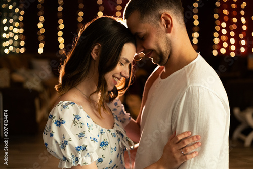 Obraz na plátně Young couple embracing tenderly with warm bokeh lights in the background