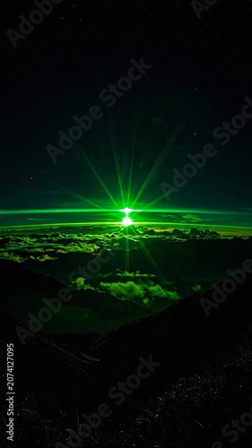 Green light shines brightly over dark mountain clouds at night