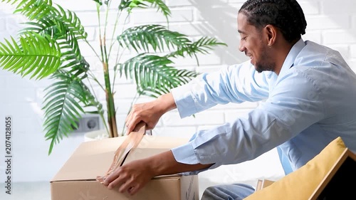 young latino man packing moving boxes at home, preparing for relocation. Real lifestyle moment capturing the moving process indoors