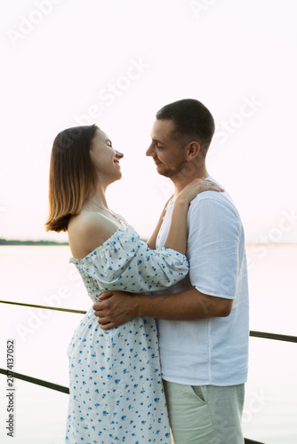 Schilderij op canvas Young couple embracing tenderly by the water at sunset