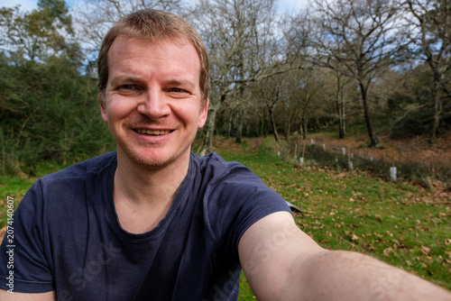 John green smiling taking selfie outdoors in forest