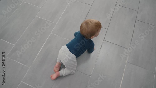 Child moving on tiled floor towards brightness. Toddler crawling in sunlit room seeking shadows and light. Young child in minimalistic home environment exploring shadows cast by window blinds