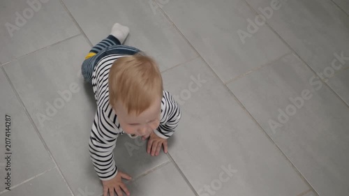 Child explores home happily. Baby practices crawling inside with soft natural daylight. Child energetically practices movement across household tiles under gentle sunlight illuminating space