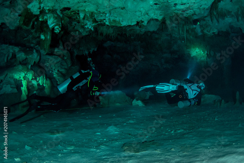 Bild auf Leinwand Scuba divers exploring crystal clear cenote caves beneath the Yucatan jungle Mex