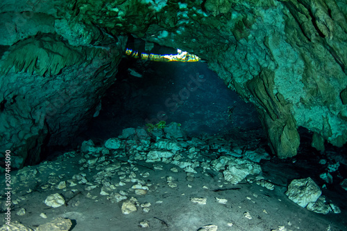Fotografía Cenote cave tunnel leading toward a bright opening with sunlight entering underw