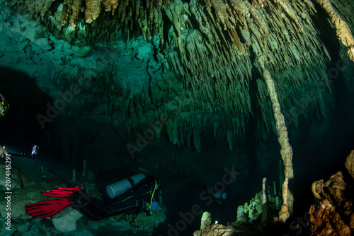 Fotografie Cave divers entering a hidden cenote underwater cave system in Mexico