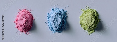 Three piles of colored powder against a gray background