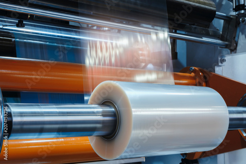 Automatic polyethylene plastic bag production machine with lighting effect. Close-up of the roller of the plastic bag production machine in the light blue scene. product packaging concept