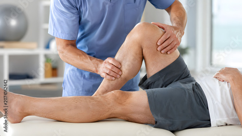 Physical therapist treating patient knee during rehabilitation