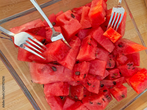 Overhead closeup of freshly cut watermelon cubes arranged in clear rectangular glass dish with 