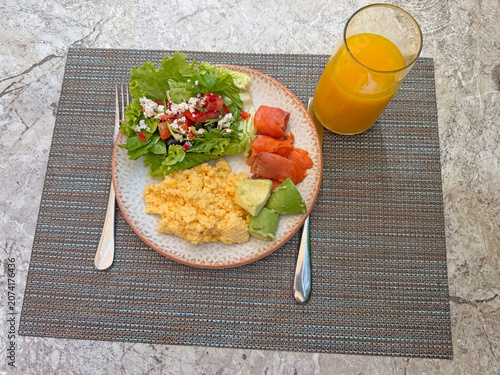 Overhead view of colorful breakfast plate with fluffy scrambled eggs, avocado, smoked salmon,
