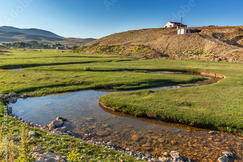 Meandering stream flows through a lush green high plateau in Antalya, Turkey
