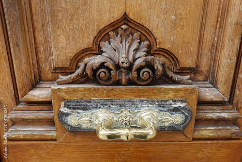 Obraz na plátne Poignée de porte ornementale sur un socle de marbre et porte en bois sculpté