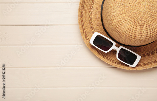 Photos A stylish straw hat and white sunglasses on light background.