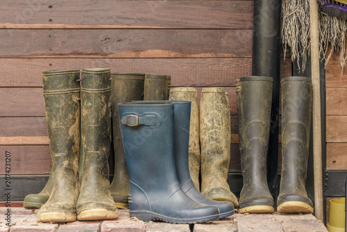 Very used and dirty wedge boots at the entrance of a farmhouse