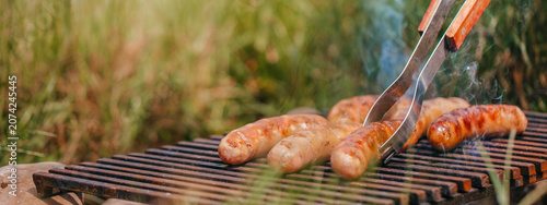 Grilling sausages on barbecue over open fire outdoors