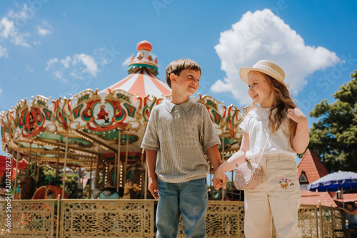 happy boy and girl on a carousel at an amusement park in the summer