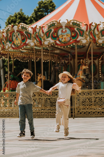 happy boy and girl on a carousel at an amusement park in the summer