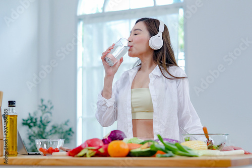 Fotografie Asian women in good spirits hold glass clean water drink while cooking refresh themselves and ensure they have enough water which helps keep their bodies refreshed energetic beneficial health
