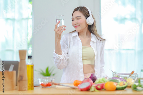 Fotografie Asian women in good spirits hold glass clean water drink while cooking refresh themselves and ensure have enough water which helps keep bodies refreshed energetic beneficial their health